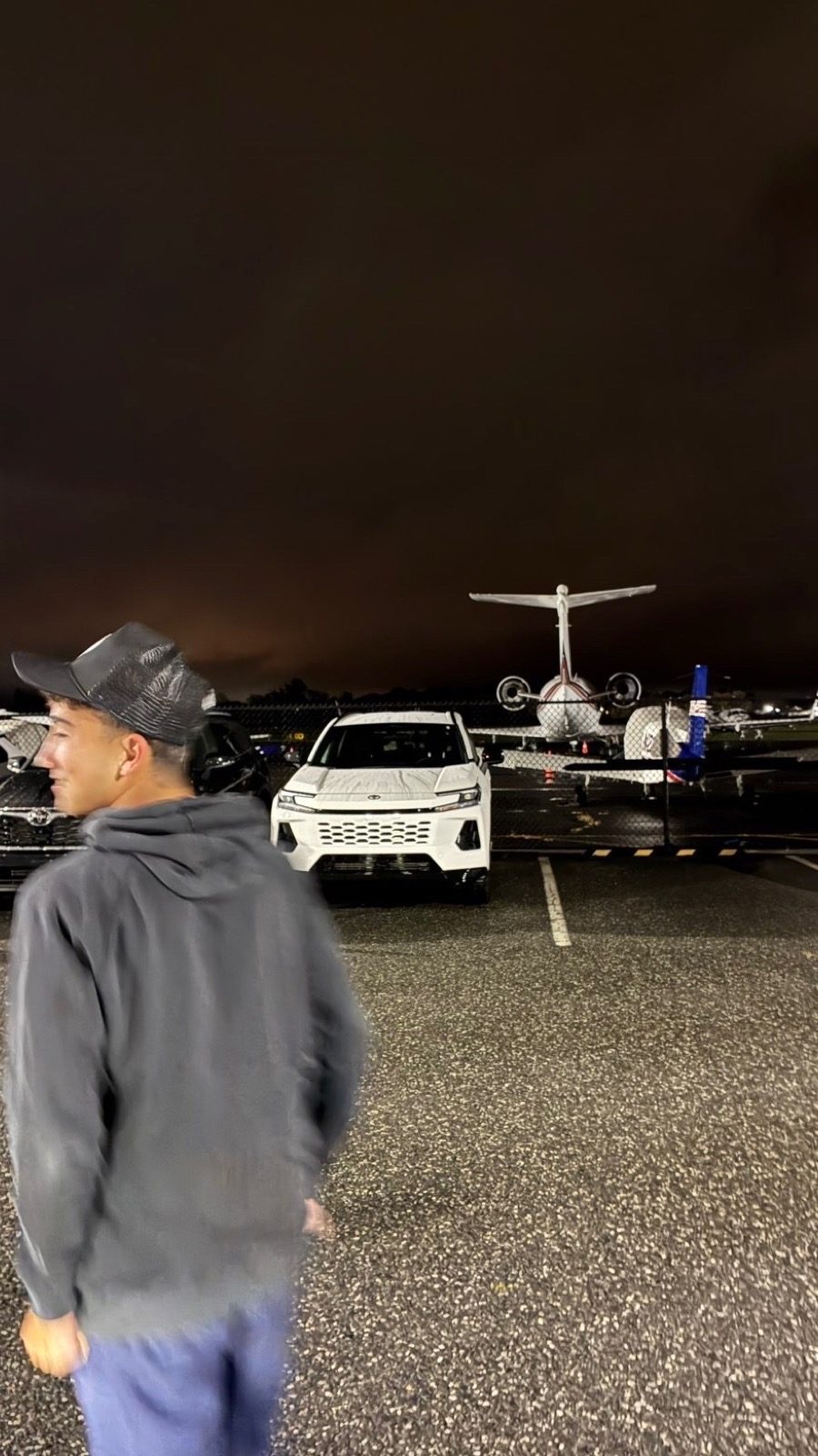 Jacob near cars and an aircraft at night