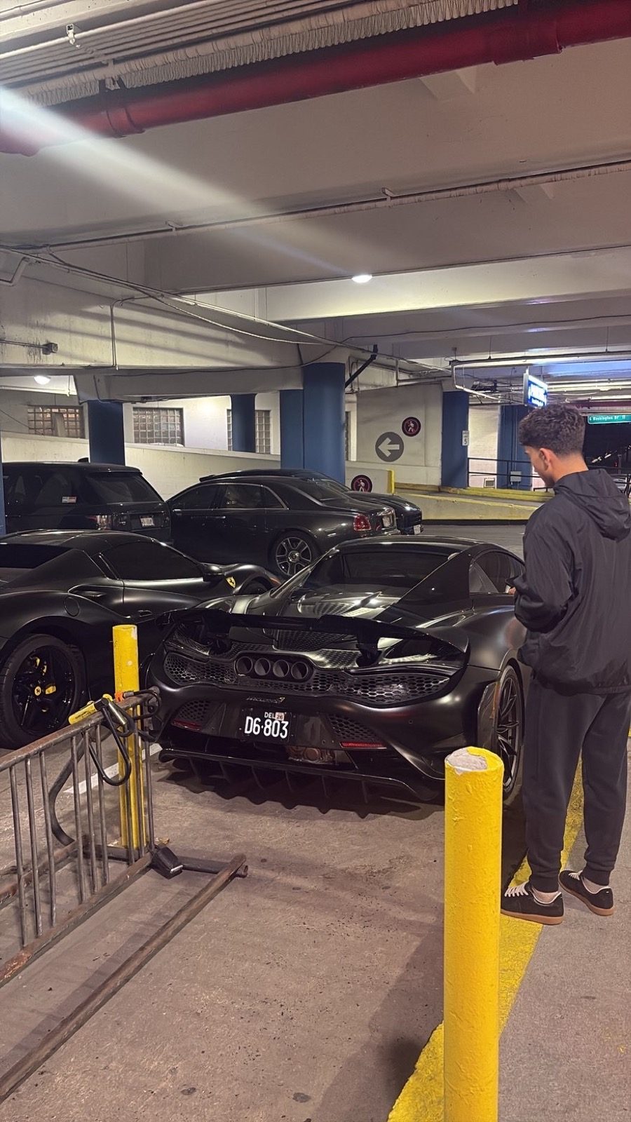 Jacob beside sports cars in a garage